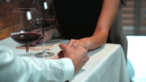 pareja tomándose de la mano durante una cena romántica en un restaurante, día de san valentín