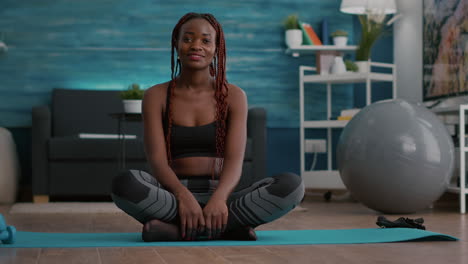 portrait of black athlete sitting in lotus position on floor enjoying morning workout