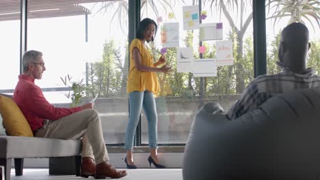 African-american-businesswoman-discussing-with-her-colleagues-over-memo-notes-on-window-at-office