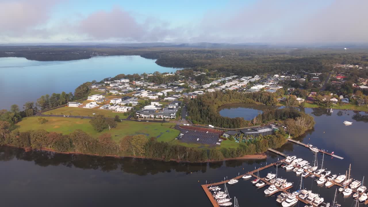 Aerial establishing of Trinity Point peninsula with marina and lush surrounding landscape, tracking right