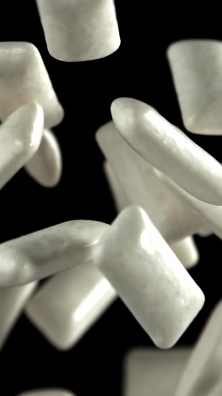 Pezzi di chewing gum bianco che cadono e galleggiano al rallentatore