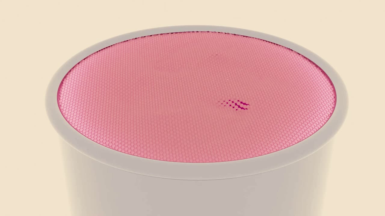 Closeup of a pink round speaker with mesh grille.