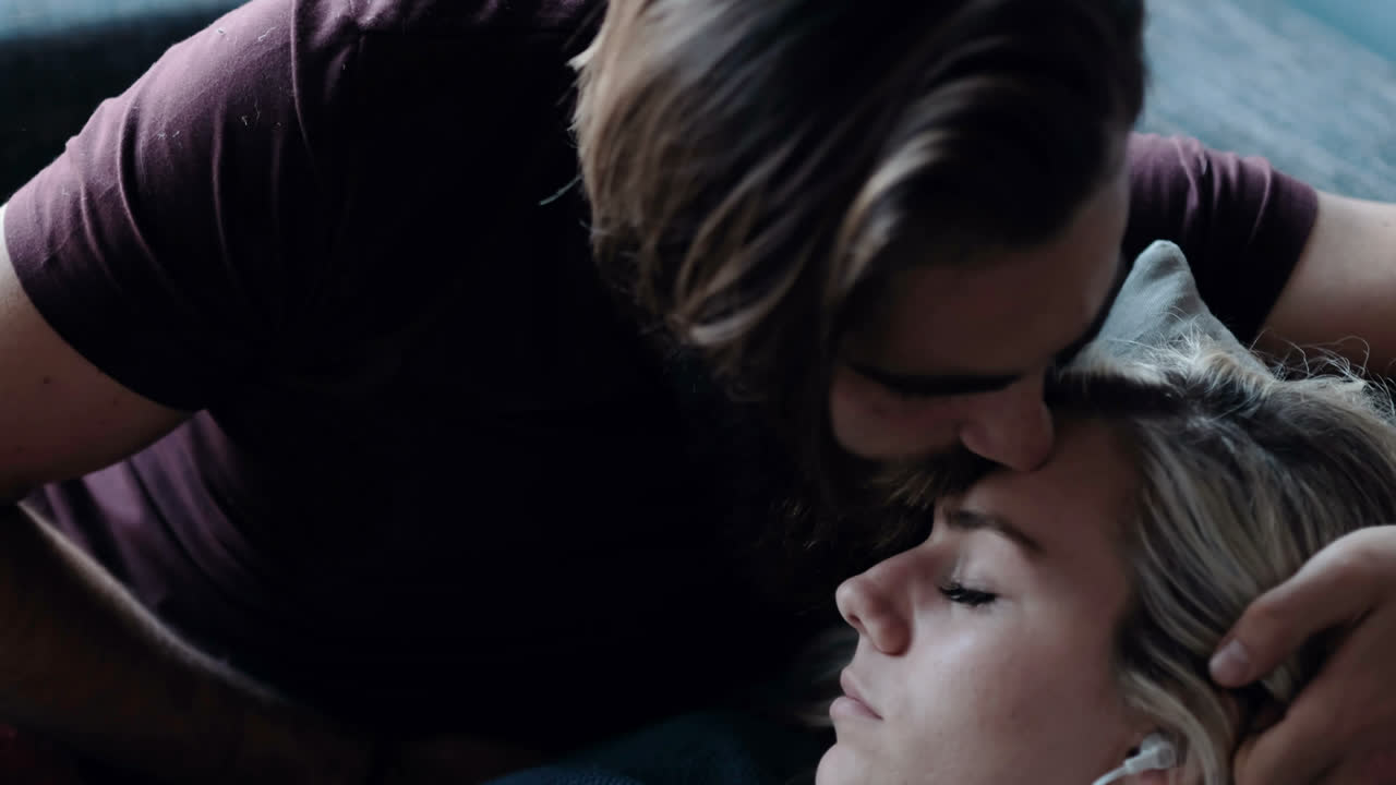 소파 4k에서 휴식을 취하는 동안 남자가 여성의 이마를 키스합니다.