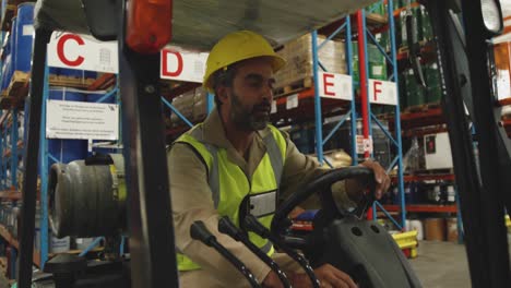 Male-worker-driving-forklift-in-a-warehouse