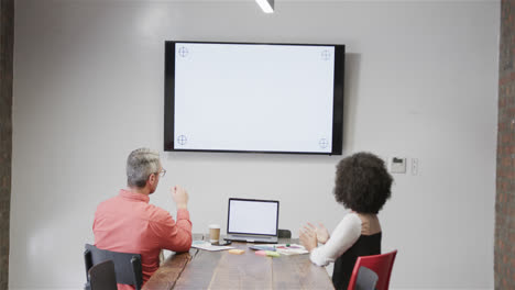 diverse colleagues having video call with laptop and monitor, copy space on screens, slow motion