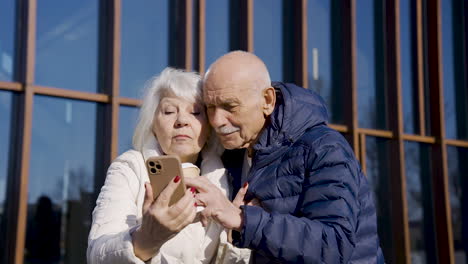 pareja mayor haciendo un selfie con smartphone en la calle en un día de invierno