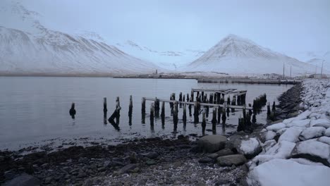 quiet space in siglufjordur with an old broken pier by the shore - monochrome shot