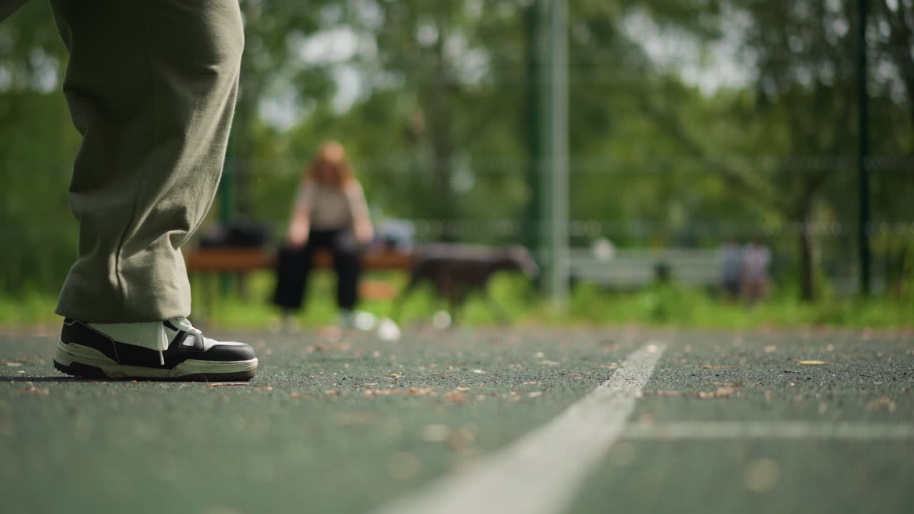 Ungdom trikser med ball, gutt demonstrerer smidige fotballferdigheter, ung mann utfører elegante fotballbevegelser på banen, tenåring viser stilig fotarbeid med fotball midt i parklandskapet