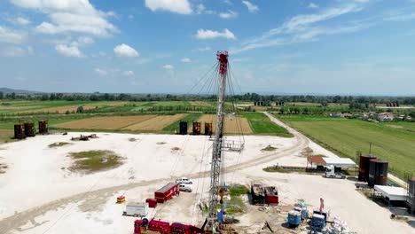 pozo de petróleo con equipos de perforación en una tierra industrial rodeada de campos agrícolas