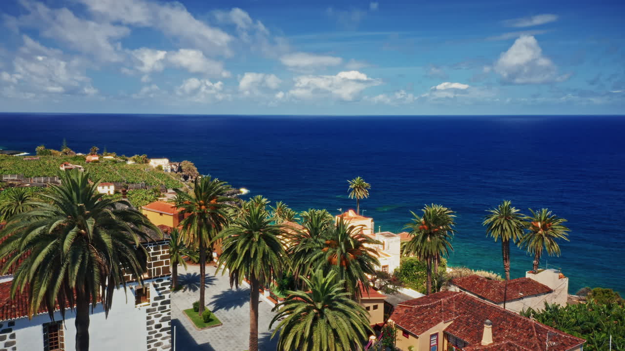 Aerial drone shot over the coastline of La Palma, Canary Islands, Spain. High view of the turquoise ocean, rugged coastline, banana plantations and the small local town. Summer holidays destination.