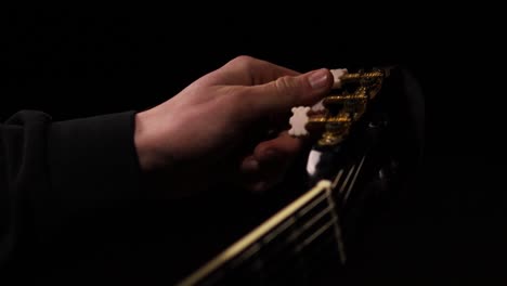 detail shot with great lighting of man tuning a guitar