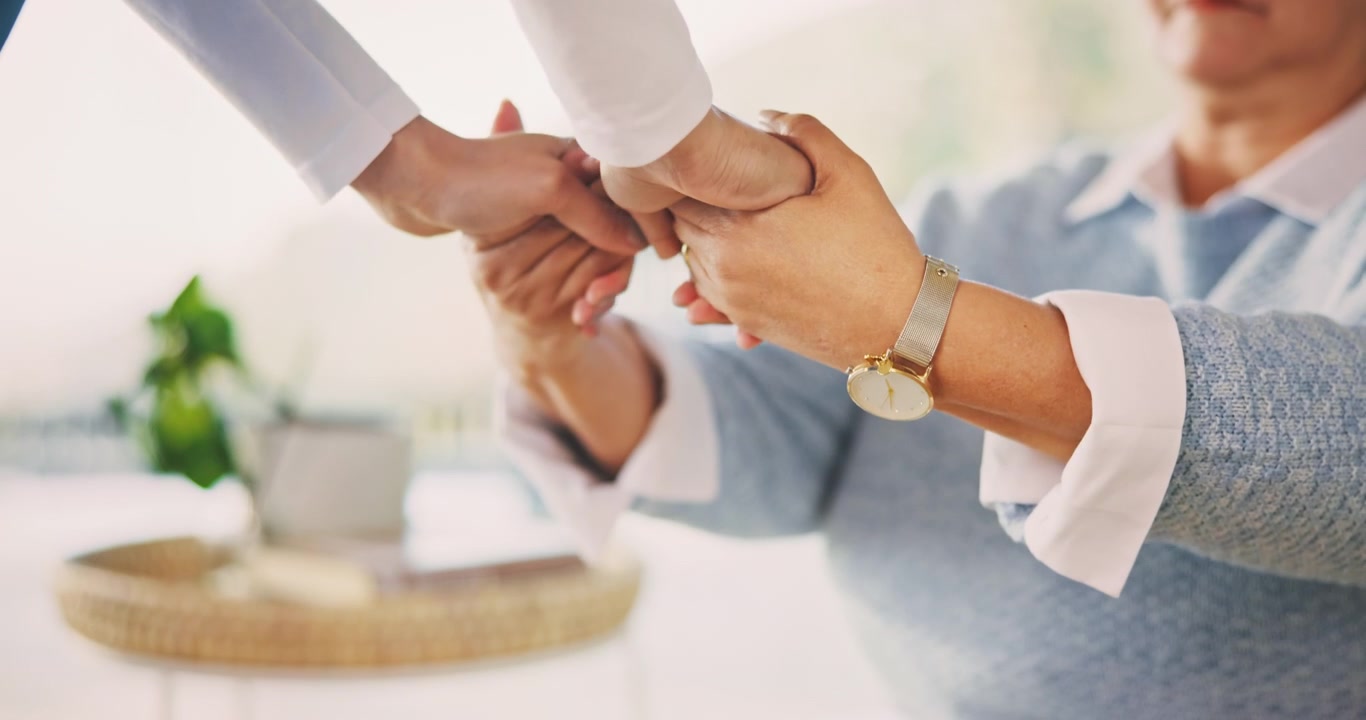 Young Person Holding Hands with Elderly Woman for Comfort