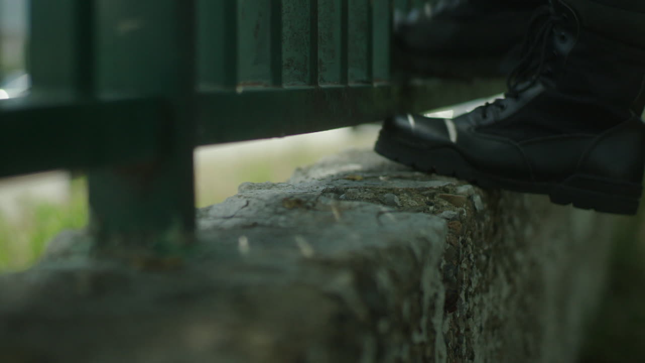 Military Boots Leaning on a Fence