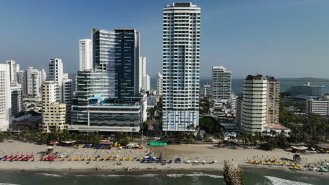 Vista-Aérea-Frente-A-La-Playa-Y-Alto-De-Bocagrande,-En-La-Soleada-Cartagena,-Colombia---Seguimiento,-Disparo-De-Drones