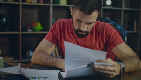 Young-business-man-working-with-pen-with-business-documents-in-office-at-evening