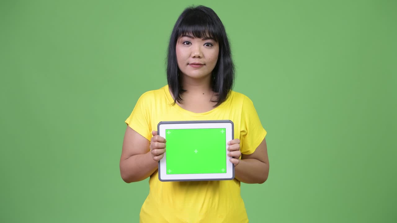 Beautiful happy Asian woman showing digital tablet
