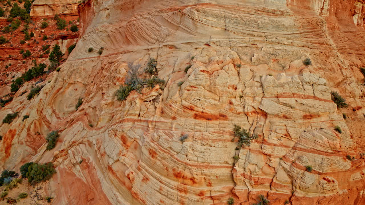 Overhead drone footage explores the intricate rock designs of a red canyon wall.