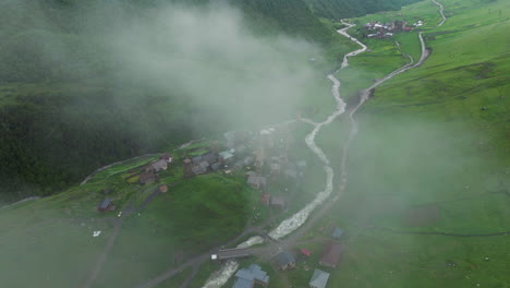 nubes de niebla sobre una aldea remota con un río que fluye en ushguli en el alto svaneti, georgia