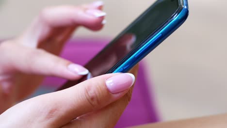 una mujer está sentada en un café con un teléfono inteligente en las manos con una maqueta de pantalla verde. la chica utiliza activamente el teléfono para sus propios propósitos. contenido, videos, blogs.