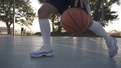 Close-Up-Of-A-Female-Basketball-Player-In-White-Golf-Socks-And-Blue-And-White-Sneakers-Training-Outdoors-On-The-Court,-Bouncing-A-Ball