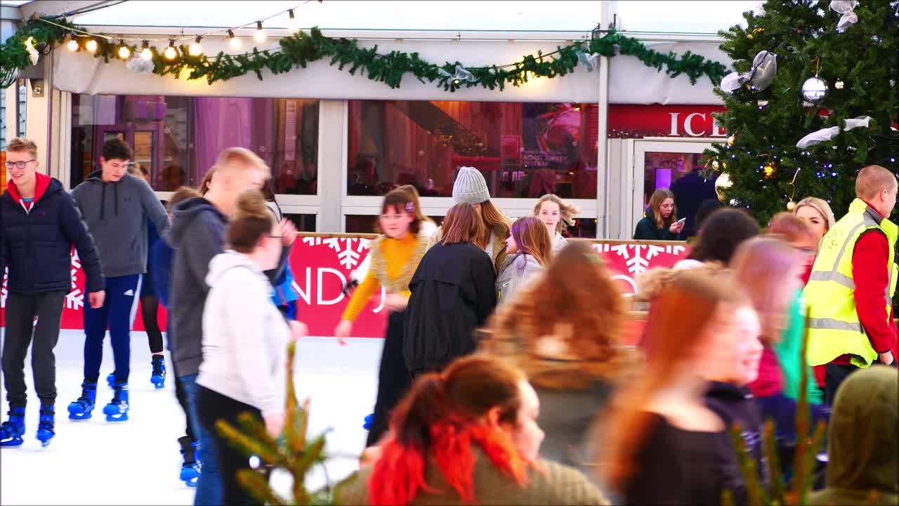 Winchester christmas market people ice skating around a large christmas tree, Winchester University Logo. Christmas Ice rink activity, fun skating