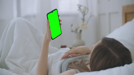 Mujer-Joven-Acostada-En-La-Cama-Haciendo-Una-Videollamada-Al-Médico-Mirando-La-Pantalla-Verde-Del-Cromakey