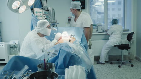 surgeon with team work with patient in room. cardiologist doctor with assistants conducts complicated artery bypass surgery in clinic. heart pathology