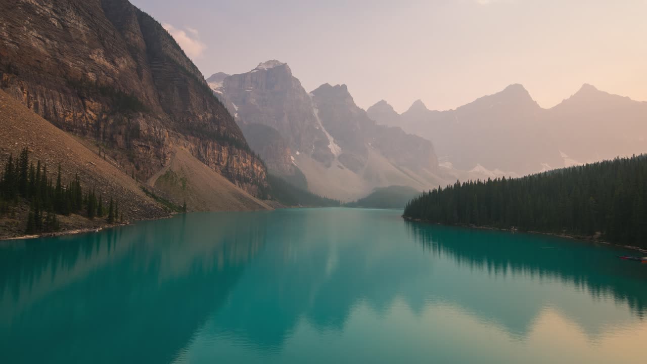 Lago Moraine nel Parco Nazionale di Banff con acqua glaciale turchese, circondato da aspre cime montuose e una fitta foresta di pini, che crea un iconico paesaggio alpino canadese.