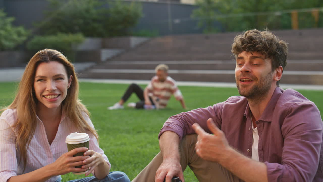 웃는 친구들이 앉아있는 공원 대출 클로즈업. 행복한 학생들이 커피 컵을 들고 있습니다.