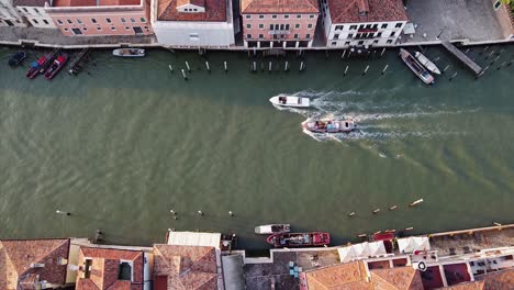 aerial top-down view of boats traveling through the residential canals of venice, italy