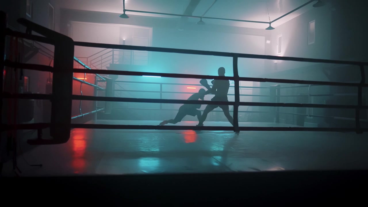 Silhouetten von Boxern beim Sparring in einem rauchigen Ring mit Neonlichtern