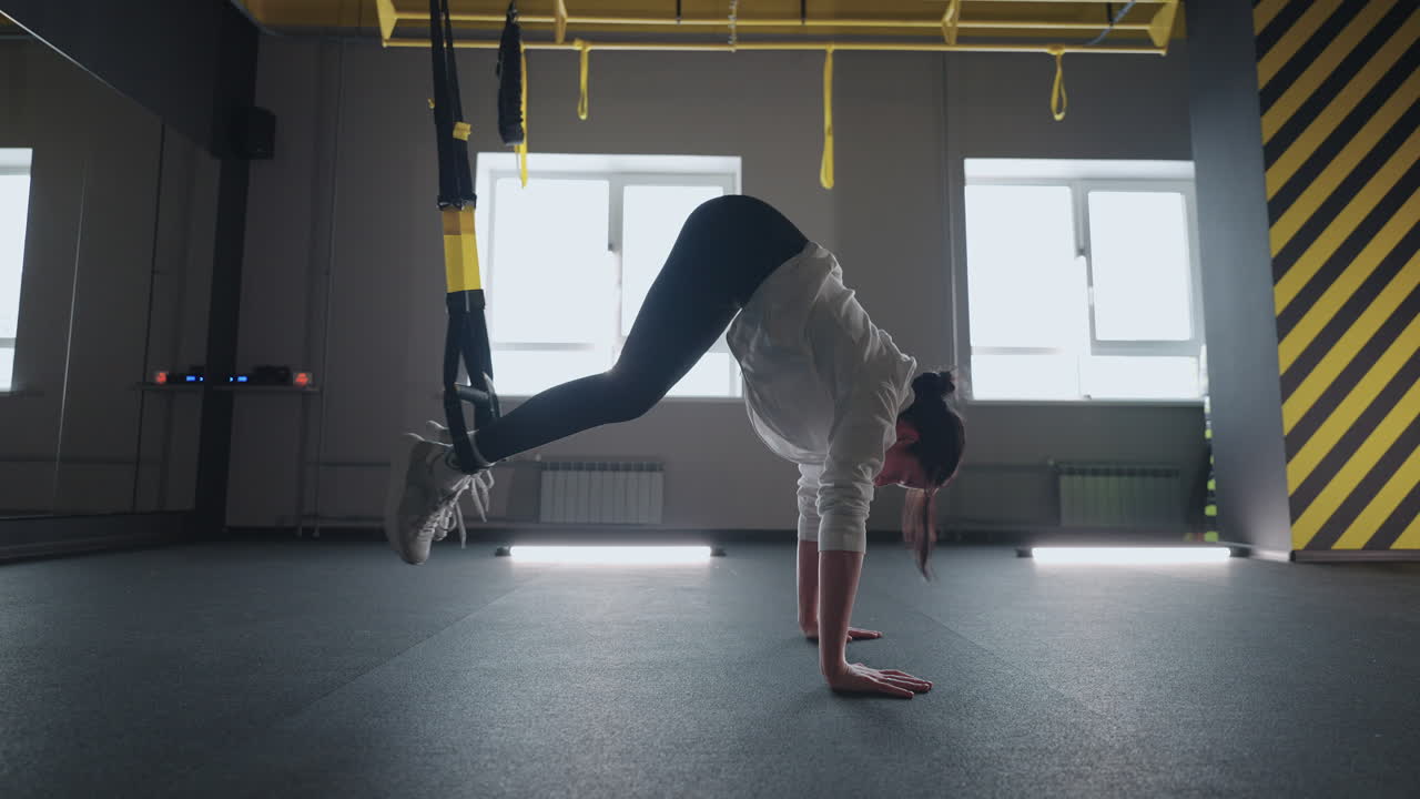 fitness TRX training exercises at gym woman push-up workout. Attractive woman doing exercise for hands in gym. core abs crossfit oblique training with fitness straps in the gym's studio. TRX