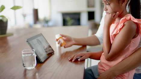 Biracial-mother-and-sick-daughter-at-home,-having-tablet-video-call-with-female-doctor,-slow-motion