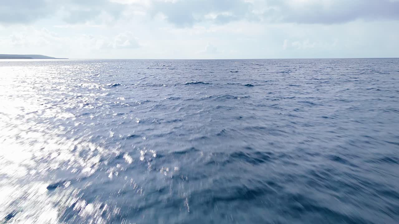 바다의 파도 위에 낮은 공중 도리 구름이 가득한 하늘과 빛이 반이는 해안으로 굴러