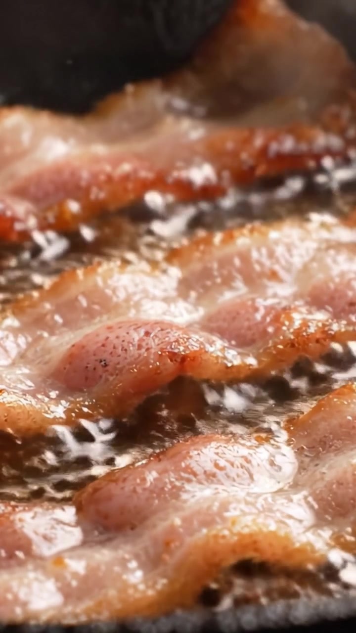 Pancetta sfrigolante in padella: croccantezza irresistibile, cotta alla perfezione con bordi croccanti e un aroma delizioso per tutti i tuoi piaceri della colazione.