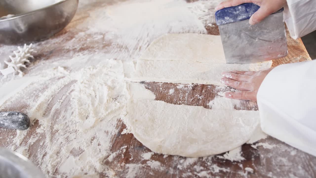 베이커리 부 ⁇ 에서 일하는 아시아 여성 베이커, 슬로우 모션으로 카운터에서 반죽을 잘라