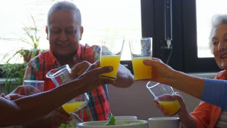 senior friends toasting glasses of juice on dining table 4k