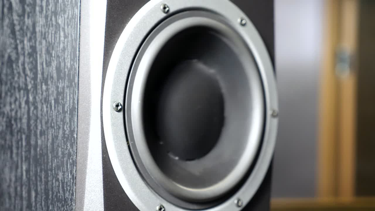 レコーディングスタジオで動くサブウーファーのクローズアップ。低周波の大きな音楽を聴いて脈動し振動する黒いスピーカー。現代のハイファイラウドスピーカーの振動板の動作。スローモーション