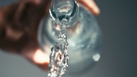 fresh, clear, healthy water flowing out of elegant glass bottle, stay hydrated in life, care for yourself, highspeed, slowmotion, closeup