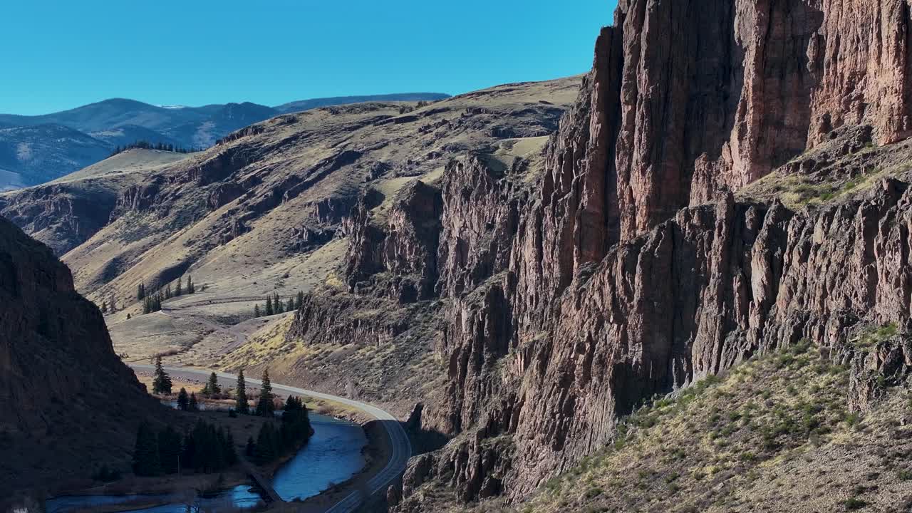 A cinematic, 70mm zoomed-in aerial shot of the beautiful yet extreme terrain and sharp cliffs of Wagon Wheel Gap, over the Rio Grande, near the infamous mining town of Creede, Colorado.