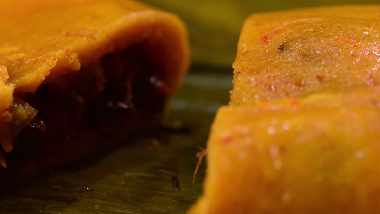 Slow motion, detailed view of a freshly cooked, traditional Venezuelan hallaca with savory stew filling, spinning on its green banana leaf wrapper