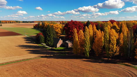 autumnal farmlands with colorful trees and a farmhouse