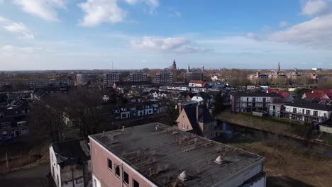 approach of former youth prison facility, now abandoned waiting for demolition and refurbishment of the moated plot field revealing wider cityscape of zutphen residential neighbourhoods and city