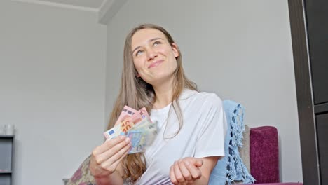 joven rica feliz haciendo un ventilador de billetes de euro, vista frontal