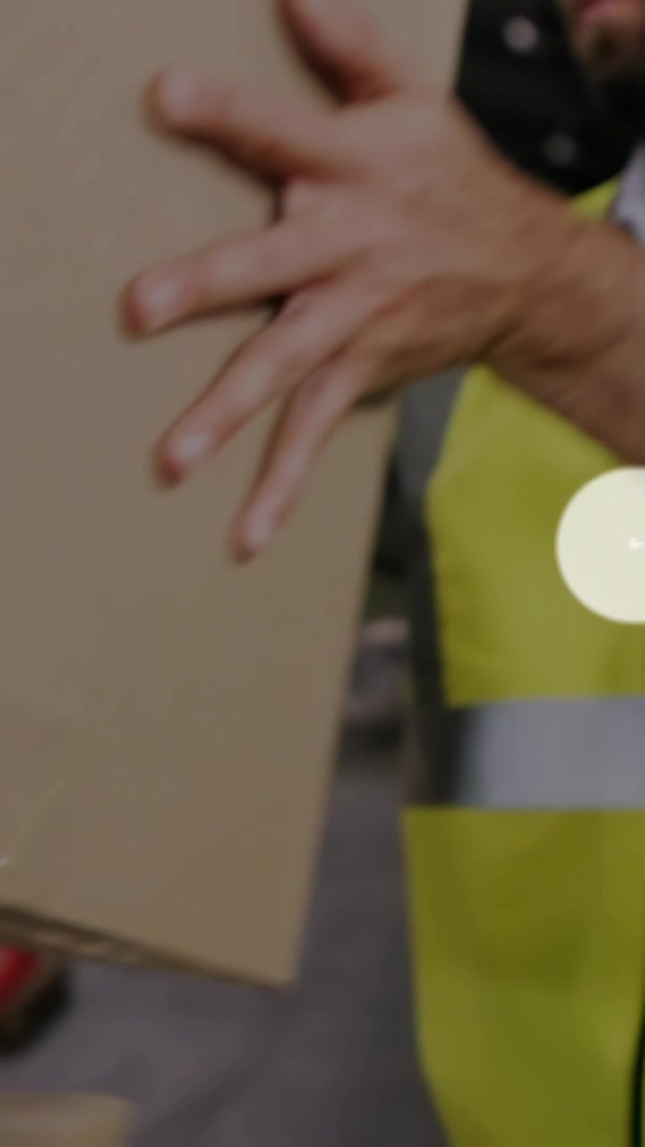 Vertikal video: Logistikprofessionel flytter kasser med palleløfter, hvilket skaber et overlay af brugerikoner for udgående forsendelser.