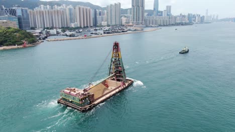 remolcador tirando de una barcaza cargada con arena fresca excavada a lo largo de la costa de hong kong, vista aérea