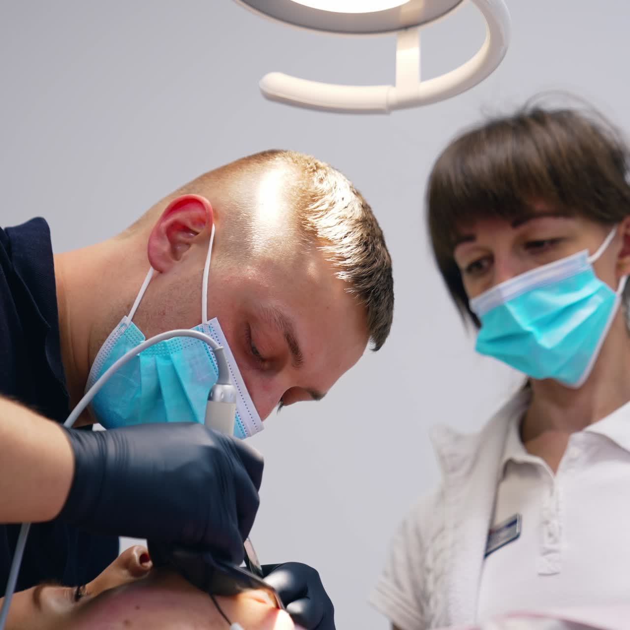 Una coppia di medici stomatologi al lavoro sui denti di un paziente. Trattamento odontoiatrico dei denti