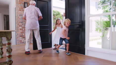 young brother and sister arriving home with grandparents