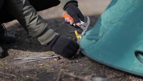 setting up camping hammering down tent stake nails to ground, close up