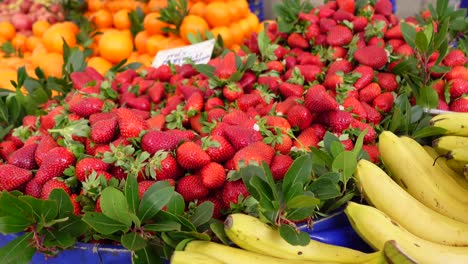 fresas y plátanos en un puesto de mercado